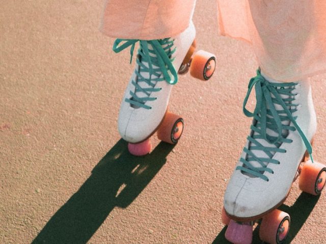 A GIRL WEARING WHITE IMPALA QUAD ROLLER SKATES ON A TENNIS COURT (RETRO/VINTAGE AESTHETIC).