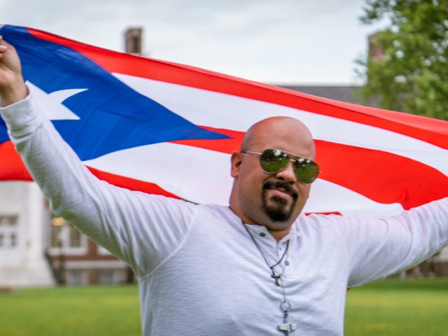 Brandon holding the Dominican Republic flag in front of Bunce hall.