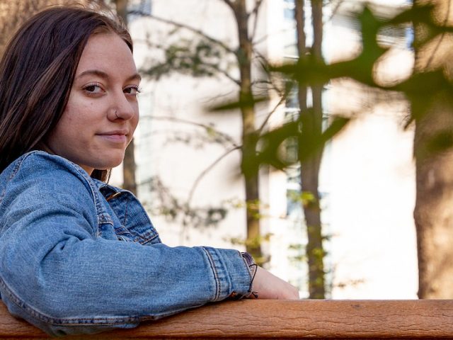 Lexi sits on a campus bench and looks over her shoulder.