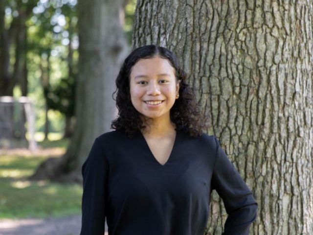 Erika poses in front of a tree.