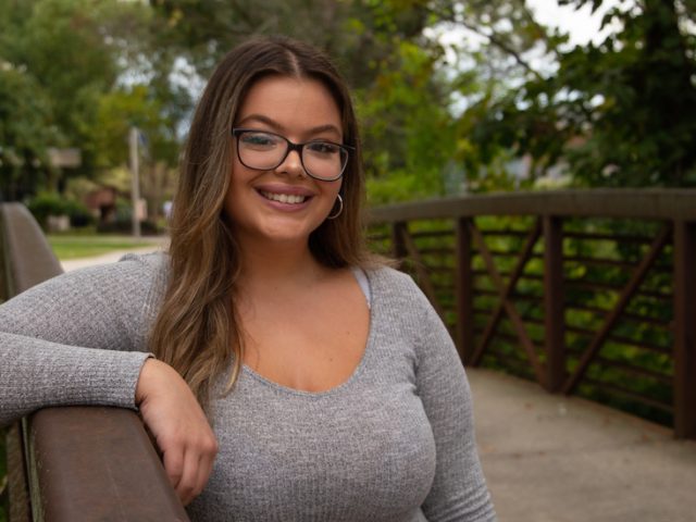 Serina stands against the bridge by the Student Center.