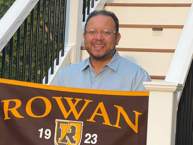 Byron holds a Rowan University flag.