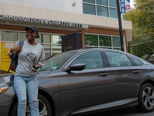 Nene leans against her car outside of the Victoria building.