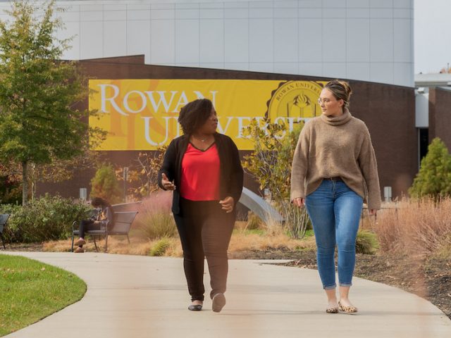 Aeberli walks with Dr. Nicole Vaughn in front of Wilson Hall.