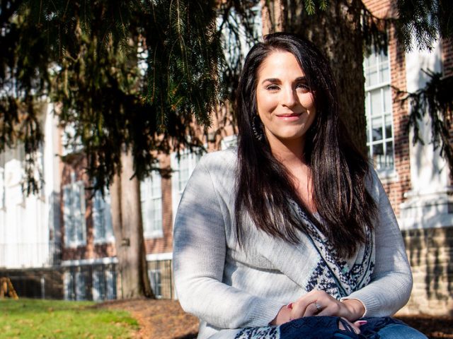 Angela sits under a tree with Bunce Hall in the background.