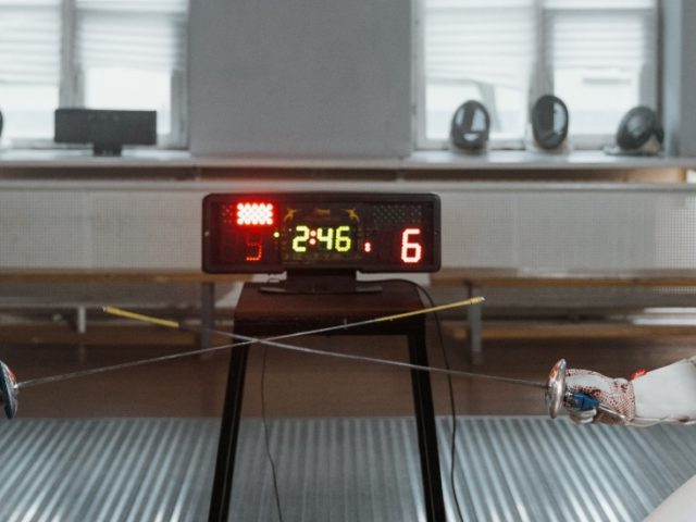 Two people fencing in full equipment.