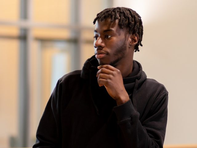 Ahmad looks to the side while leaning against a railing in Business Hall.