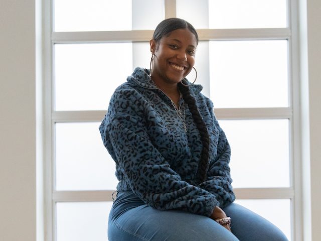 Kya smiles and sits in the lobby of Campbell Library.