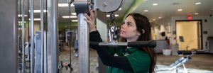 Rec Center student worker checks on gym equipment in one of the fitness rooms.
