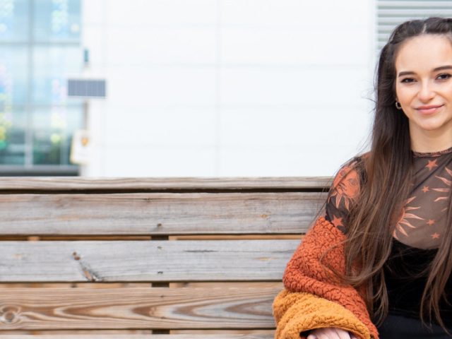 Logan is posing on a bench in front of one of Rowan's buildings.