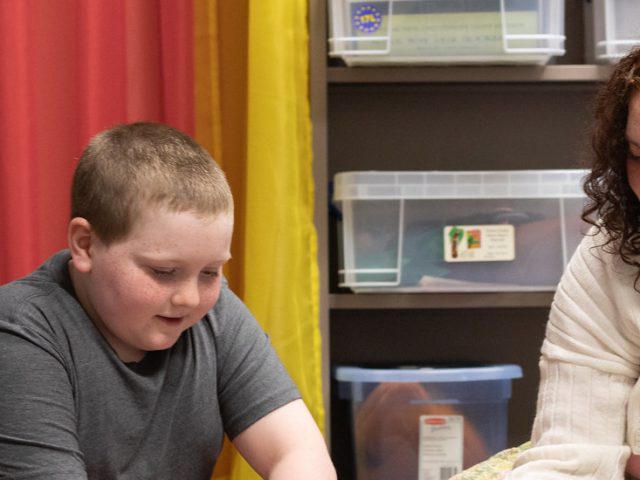 Gabriella Lugo is diligently working with a student in a classroom.