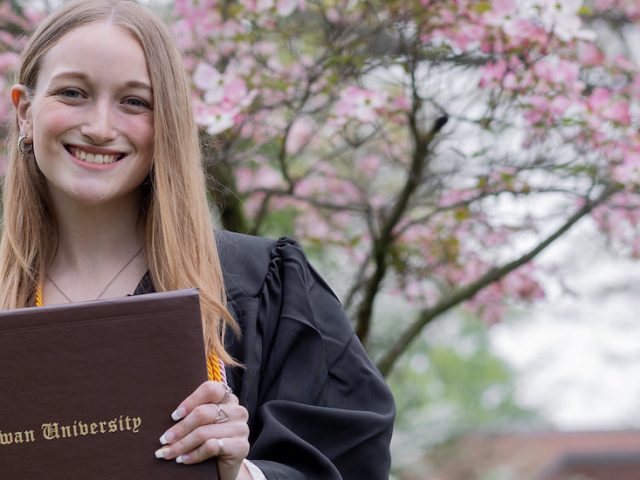 Kaya smiles, holds her diploma.