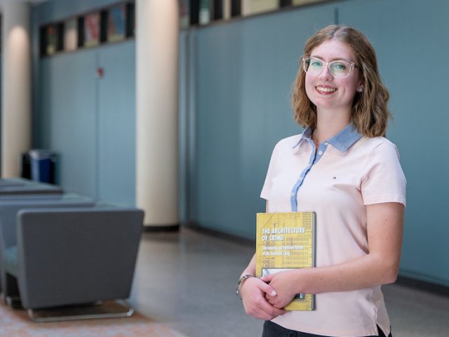 Kathryn holds a textbook. in inside