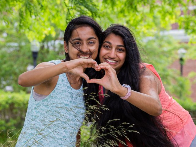 Two friends pose for Best Friends Day by joining their hands together to form a heart.