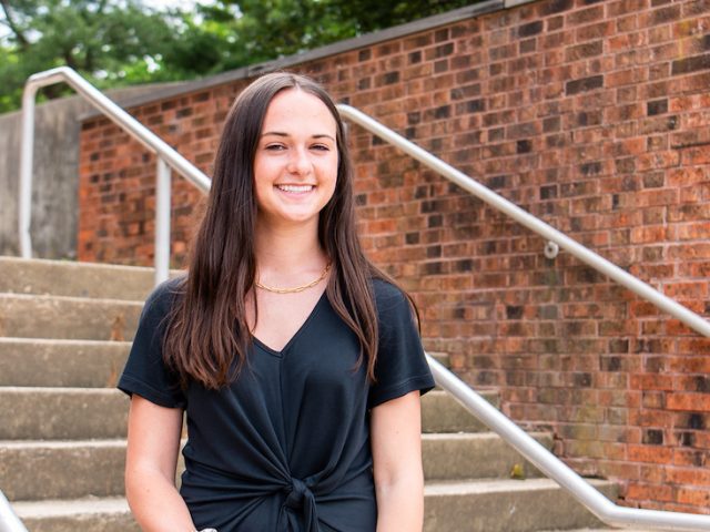 Natalie smiles outdoors on campus.