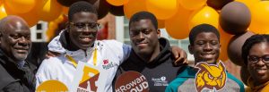 A family is posing in front of the Accepted Students Day setup and is smiling.