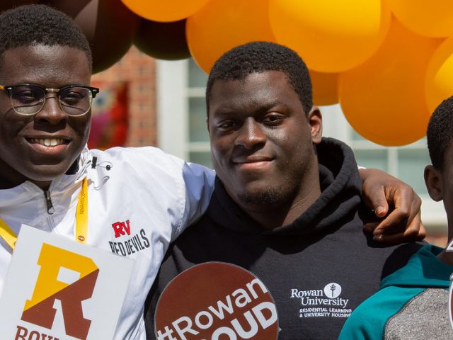 A family is posing in front of the Accepted Students Day setup and is smiling.