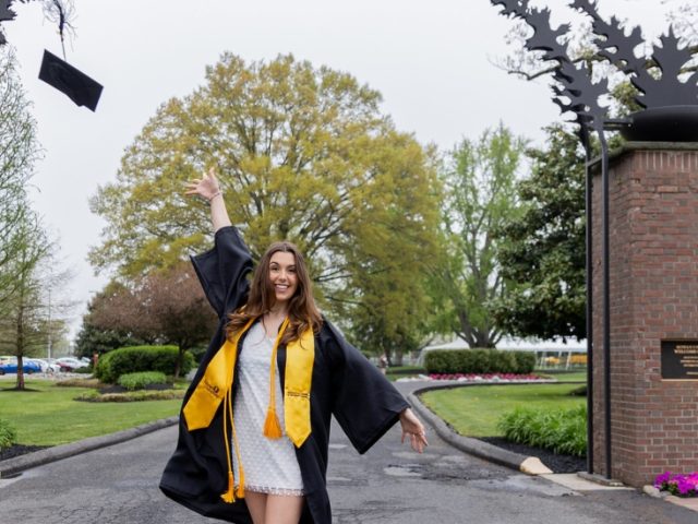 Loredonna throws her cap up in the air in front of the Rowan arch.