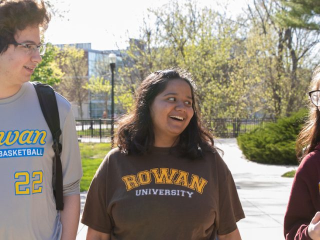 Three friends are walking and talking on campus.