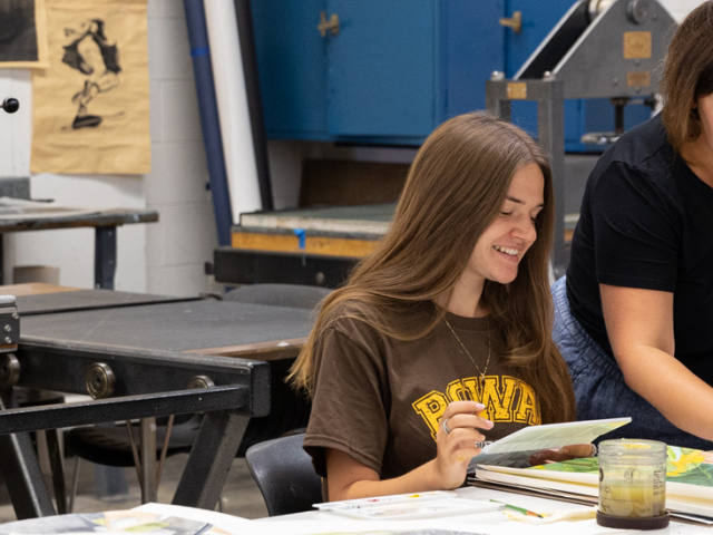 Brooke talks to professor Alicia Finger while working on a painting in class.