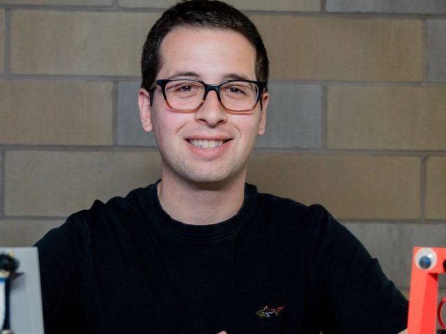 ECE major Jack Campanella sits with robots from the Rowan club from which he is president.