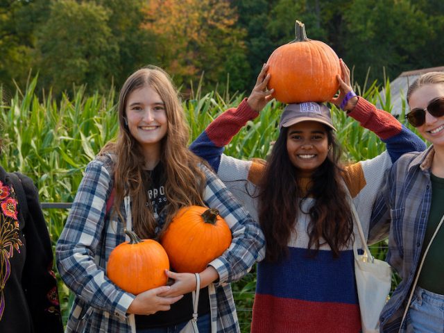 Rowan University students smile with pumpkins they found at nearby Creamy Acres Farm.