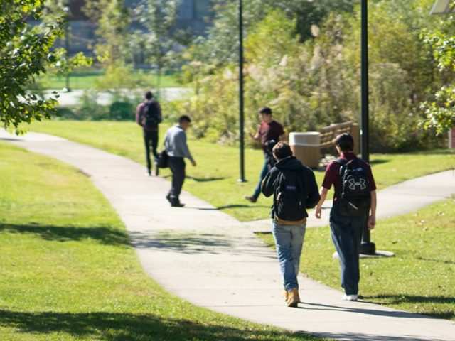 Students walking on a grassy path behind Wilson Hall.