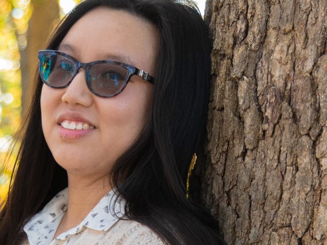 Suzie poses against a tree.