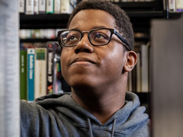 Rowan Health and Science Communication major Sedrick looks for a book in the Campbell Library.