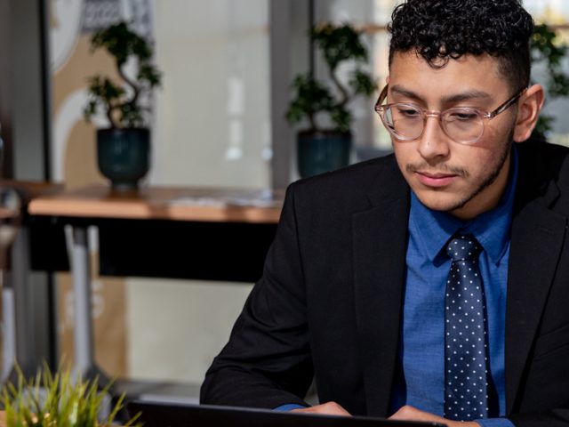 Jacob reads from a laptop, seated in Business Hall.