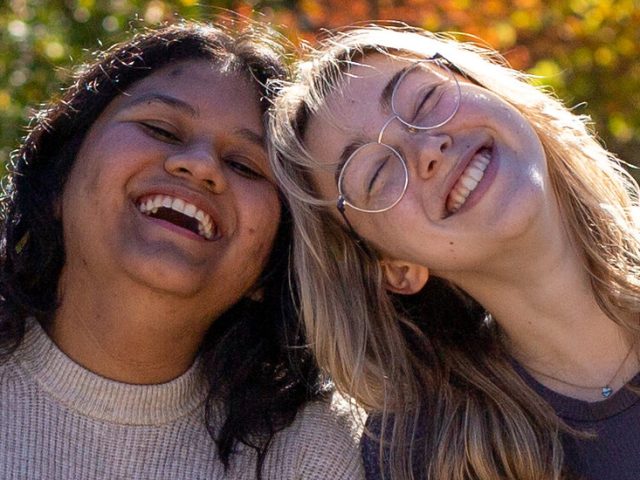 Rowan University HCI contributor Alexa leans on a friend, laughing.