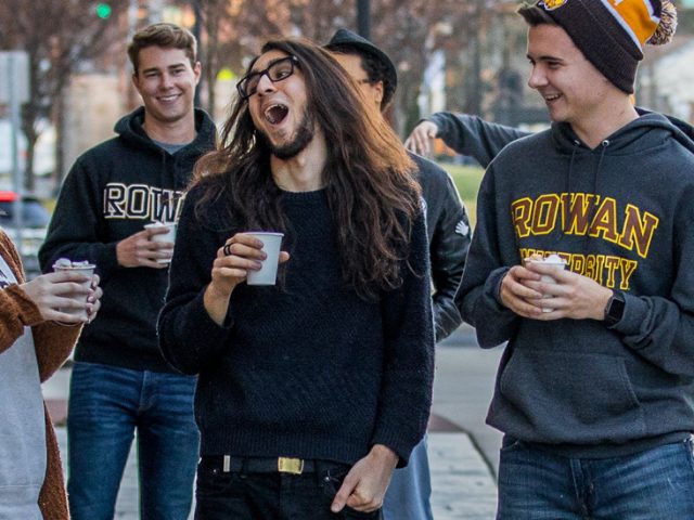 Rowan students walk down Rowan Boulevard, laughing with each other.