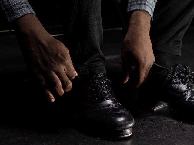 Rowan University Dance major Gregory Williams laces up his tap dance shoes.