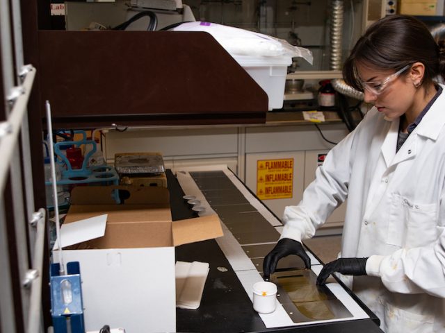 Sarah S in a lab coat doing chemical engineering research.