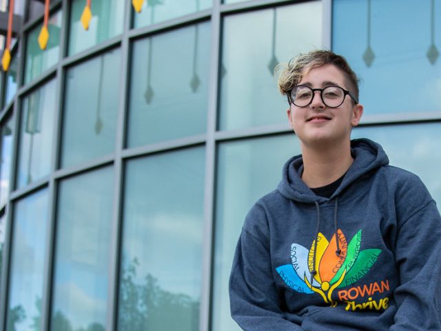 Kye is standing in front of Business Hall and smiling.