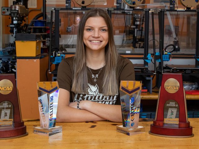 Rowan mechanical engineering student Abby smiles in front of her engineering equipment in the lab.