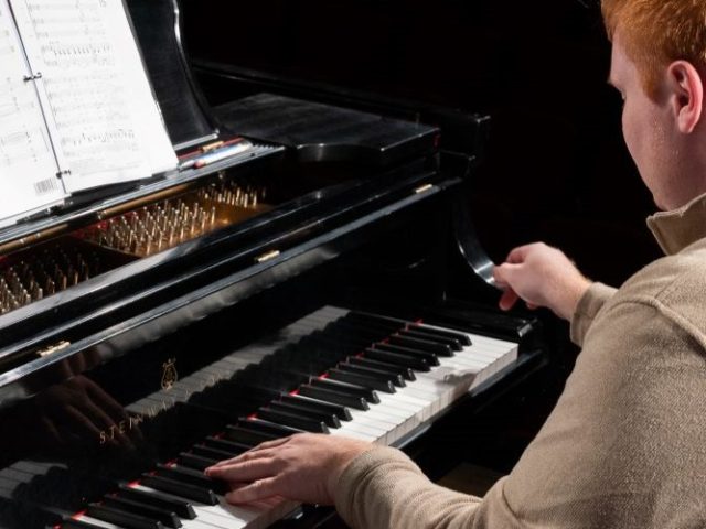 Two students playing the piano.