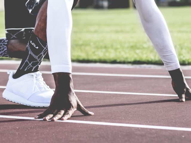 Stock image of close up of a runner's feet and hands on the track ready to run.