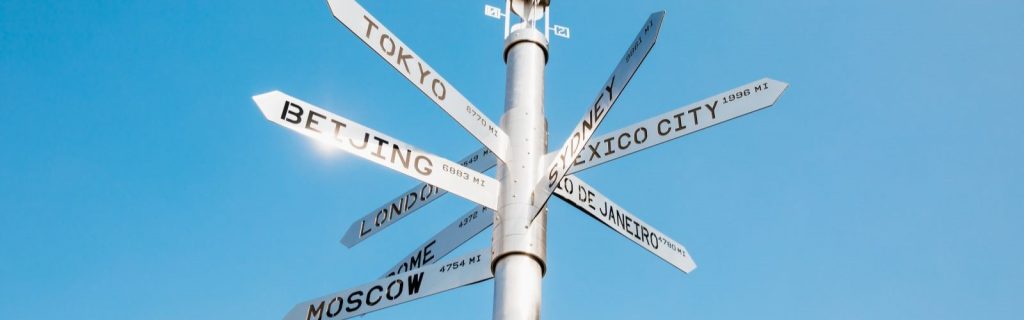 A street sign with many different countries on it.