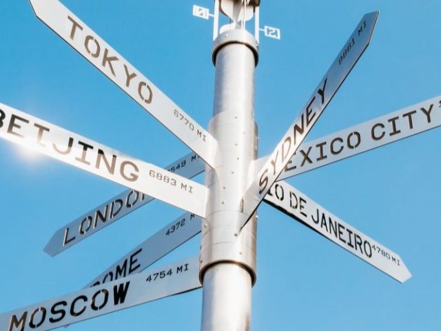 A street sign with many different countries on it.