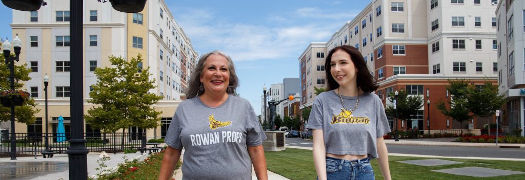 Rowan mom and daughter walk on Rowan Boulevard wearing matching shirts while smiling.