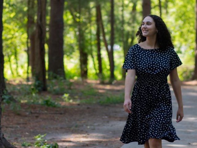 Nina Pantaleone walking along a pathway, surrounded by trees.