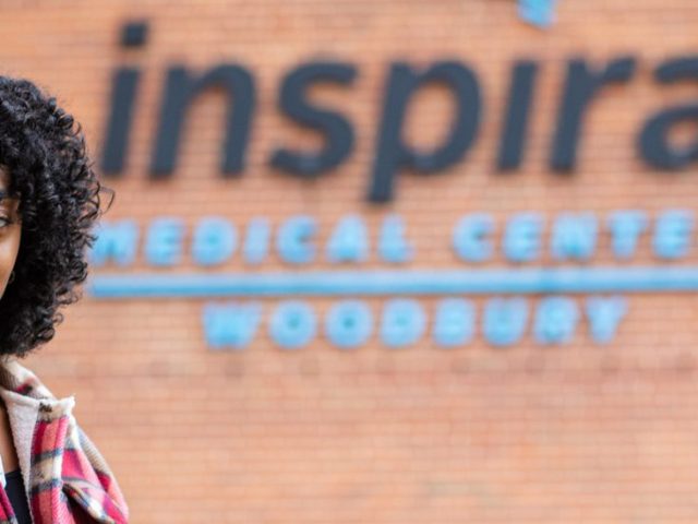 Theresa Bennett stands outside her internship at Inspira Health Network with their logo behind her.