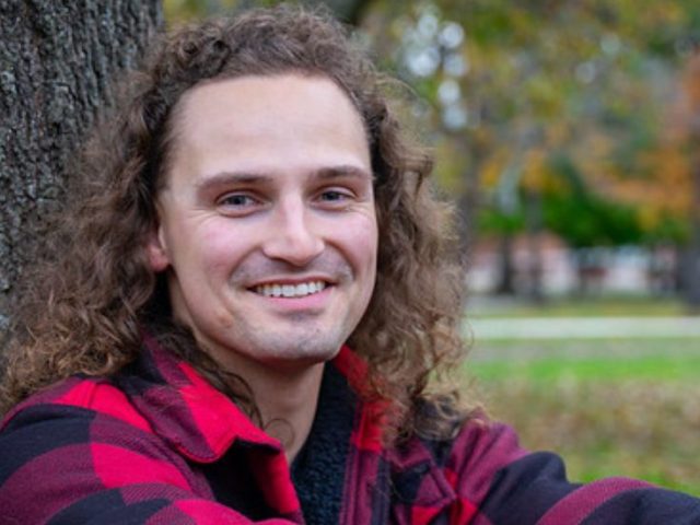 Adam Clark smiles for a portrait outdoors.