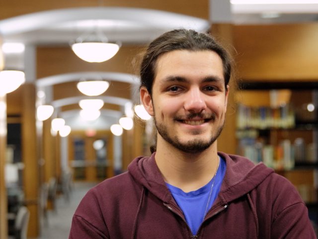 Eren stands for a portrait in the library.