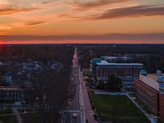 A drone shot of Glassboro, NJ, centering Rowan University, with a dramatically bright sunset behind the town.