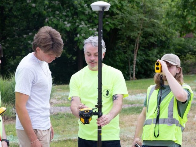 Four members of Geo Lab discuss a project while outside holding equipment.