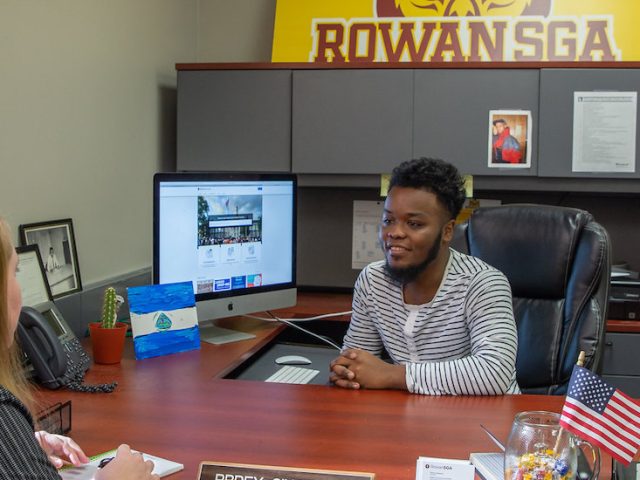 The student government association president sits at his desk for a interview.