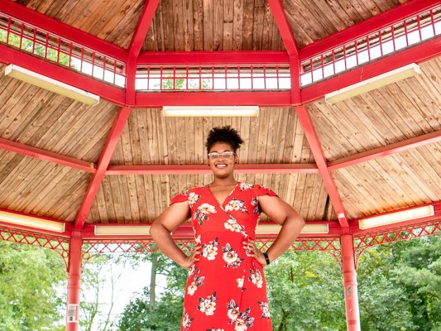 Jocelyn wearing a red dress standing under a red gazebo.