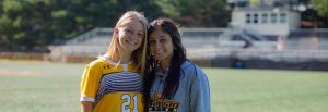 Emily stands close to a friend outside on the soccer field.
